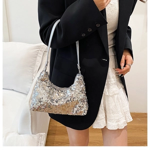 Detail of silver sequin crescent shoulder bag worn with black blazer and white skirt