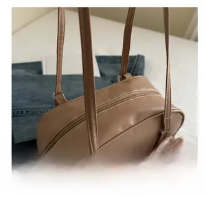 Close-up of a tan faux leather bag showing double zippers and fine stitching details