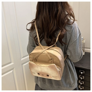 Detail of cute cat face pocket on beige mini backpack shown from rear view on model