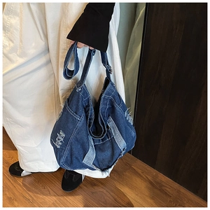 Detailed view of dark blue denim tote bag with frayed edges and distressed wash finish