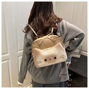 Detail of beige cat-shaped backpack featuring 3D ears and embroidered feline face details