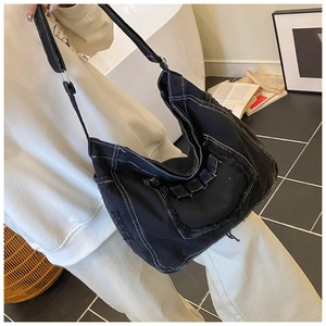 Detail of black denim crossbody bag featuring white contrast stitching and frayed edges
