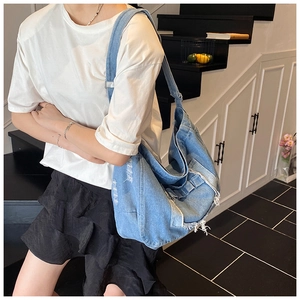 Detail of distressed blue denim crossbody bag featuring frayed edges and vintage texture