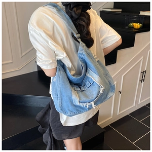 Detailed back view of a casual blue denim crossbody bag with frayed edges on a model