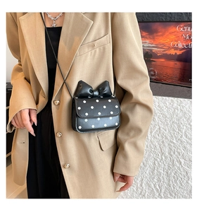 Detail of crossbody bag with white polka dots and a large 3D bow on khaki suit