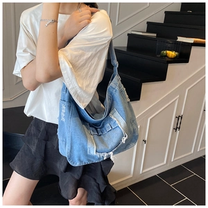 Chic distressed denim hobo bag featuring frayed edges and functional pocket detailing