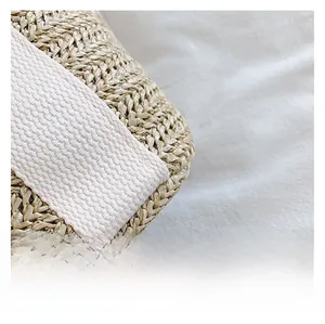 Close-up of natural straw weave texture and white canvas strap on the handmade beach bag