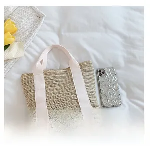Detail of woven straw handbag with white cotton handles and decorative yellow tulip
