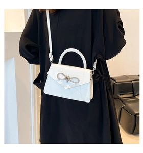 Detail of white crocodile embossed leather bag with sparkling rhinestone bow clasp