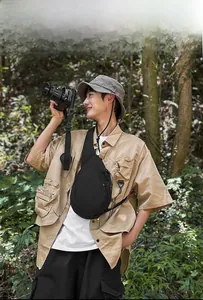 Outdoor model wearing black waterproof nylon chest bag in forest setting with camera