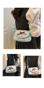 Detail of light blue checkered bag with red bow prints and silver heart charm pendant