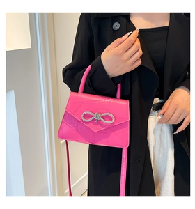 Détail du sac rose texture crocodile avec boucle nœud en strass et poignée haute