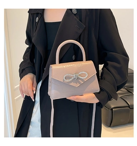 Détail d'un sac à main chic en cuir de crocodile abricot avec un nœud en strass brillant