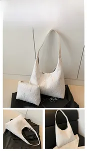 Detail view of white geometric embossed underarm tote bag with matching inner pouch set