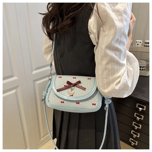 Close-up of light blue checkered crossbody bag with red bows and heart pendant detail