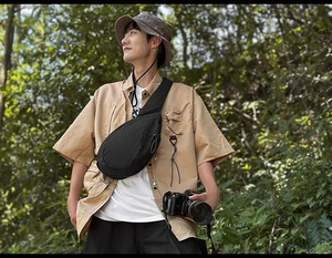 Detail of lightweight black nylon crossbody bag with drawstring on a male model outdoors