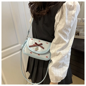Detail of light blue plaid crossbody bag with red velvet bow and silver heart pendant
