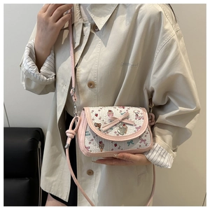 Detailed view of pink bow decor and sweet cartoon prints on a women's crossbody bag
