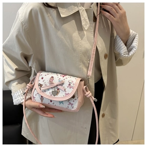 Close-up of pink bow and heart pendant on a sweet cartoon print crossbody bag