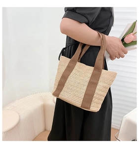 Detail of hand-woven straw tote bag with brown fabric handles and wave texture