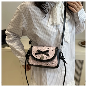 Close-up of pink ruched bag featuring black bow detail and silver heart pendant charm