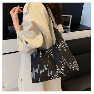 Detail of black monogram tote bag with colorful zigzag embroidery and zip closure