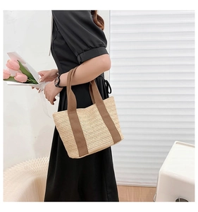 Close-up of a hand-woven straw tote bag with brown straps for summer beach vacations