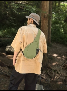 Outdoor grass green crossbody chest bag with black mesh side pocket in forest setting