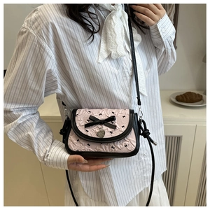 Detail of pink pleated crossbody bag featuring black bow embroidery and heart pendant