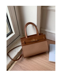 Detail of two-tone crossbody bag with brown leather, textile panels and gold metal lock