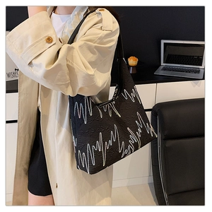 Detail of black tote bag featuring unique zigzag embroidery and leather shoulder strap
