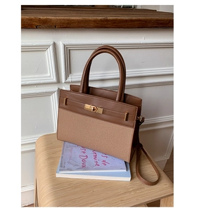 Detail of vintage brown leather and fabric handbag with a golden metallic twist lock