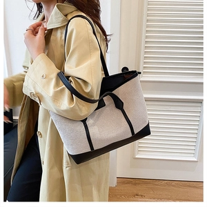 Detail of canvas and black leather contrast trim on large commuter tote bag with sturdy handles