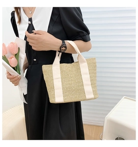 Detail of woven straw tote bag featuring cream canvas handles and natural textures