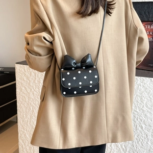 Chic black polka dot crossbody bag with a large decorative bow and slim strap