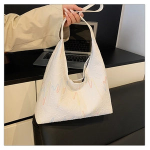 Detail of white tote bag with colorful wavy stitching and embossed texture on leather