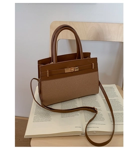 Detailed close-up of stitching on a brown leather and canvas patchwork handbag with a gold lock