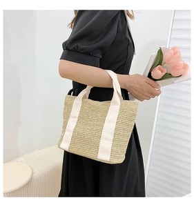 Detail of straw woven handbag with white canvas handles and decorative pink tulips