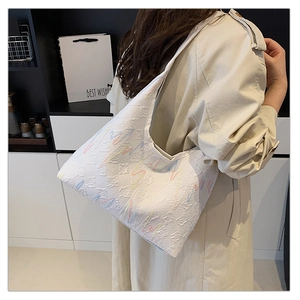 Detail of white textured tote bag with colorful embroidery on embossed leather material