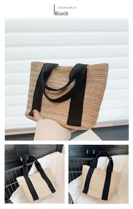 Detail of straw woven handbag with wide black fabric handles in a minimalist summer style