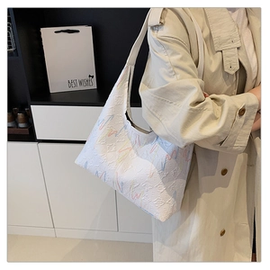 Detailed view of white hobo tote bag with rainbow embroidery worn with a beige trench coat