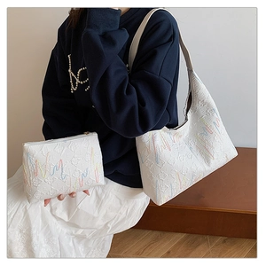 Detail of white leather tote and matching pouch with colorful wavy embroidery and embossed patterns