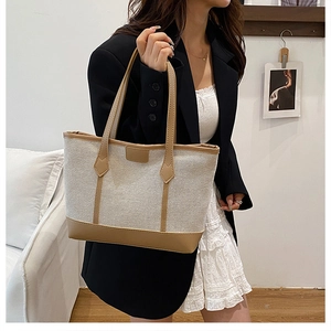 Détail d'un grand sac cabas en toile avec garniture en cuir brun porté par un mannequin