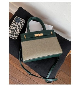 Detailed top view of a canvas and green leather handbag with a gold twist lock closure