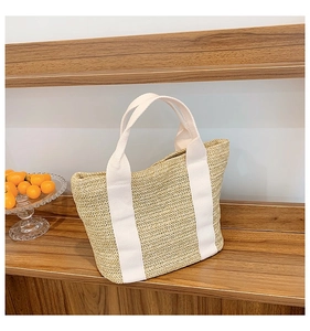 Detail of herringbone weave texture and white wide straps on a straw tote bag