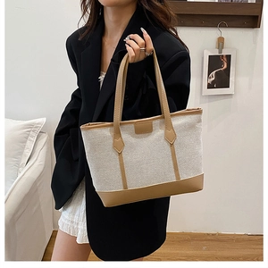 Détail du cabas en toile avec base en cuir marron et coutures renforcées sur l'anse