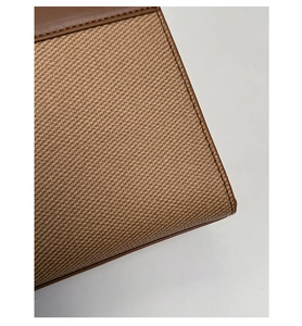 Detailed close-up of brown leather and beige twill fabric stitching on a stylish handbag