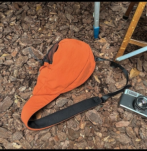 Detail of orange nylon chest bag with black mesh strap on rustic wood chip ground