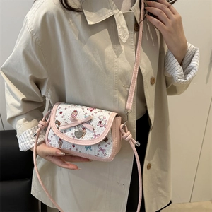 Pink bow shoulder bag with cartoon prints and heart charm shown on a model