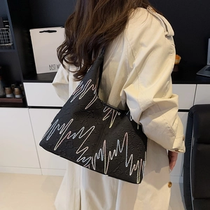 Black quilted tote bag with floral embossing and colorful embroidery shown on shoulder